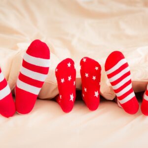 Family in Christmas socks lying on bed. Mother, father and baby having fun together.