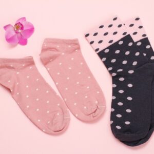 Two pairs of women socks and orchid flower on a pink background, Top view.